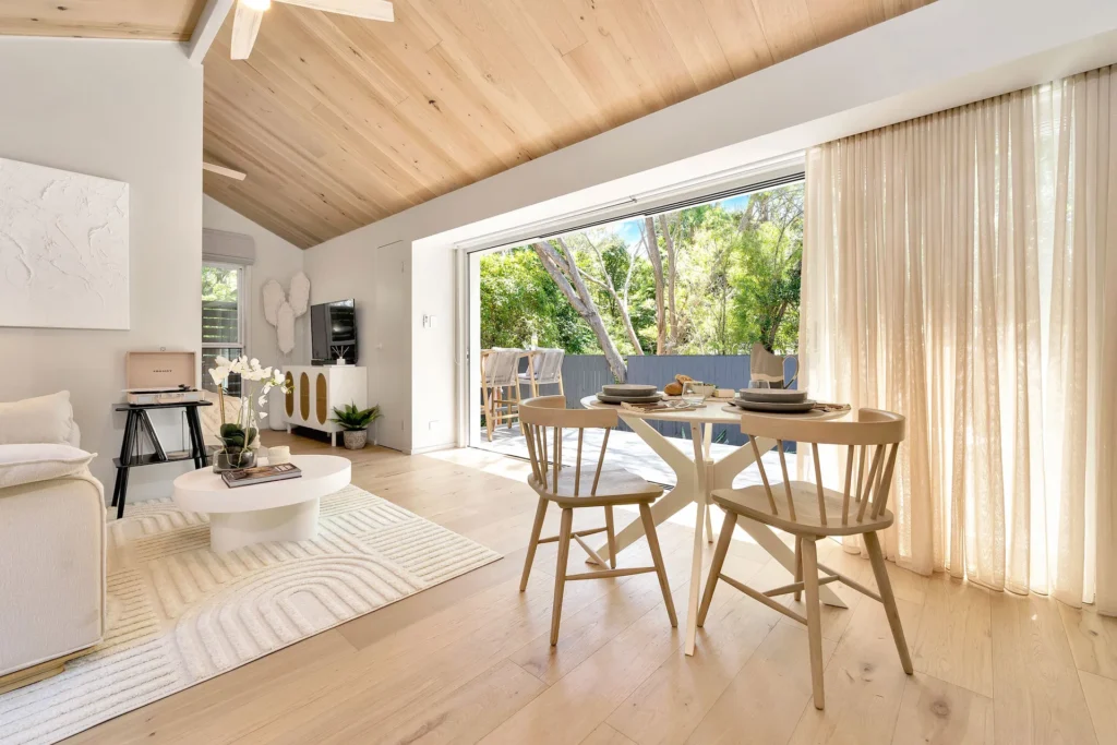 Minimalist living and dining area with timber ceilings at Akora Cabin