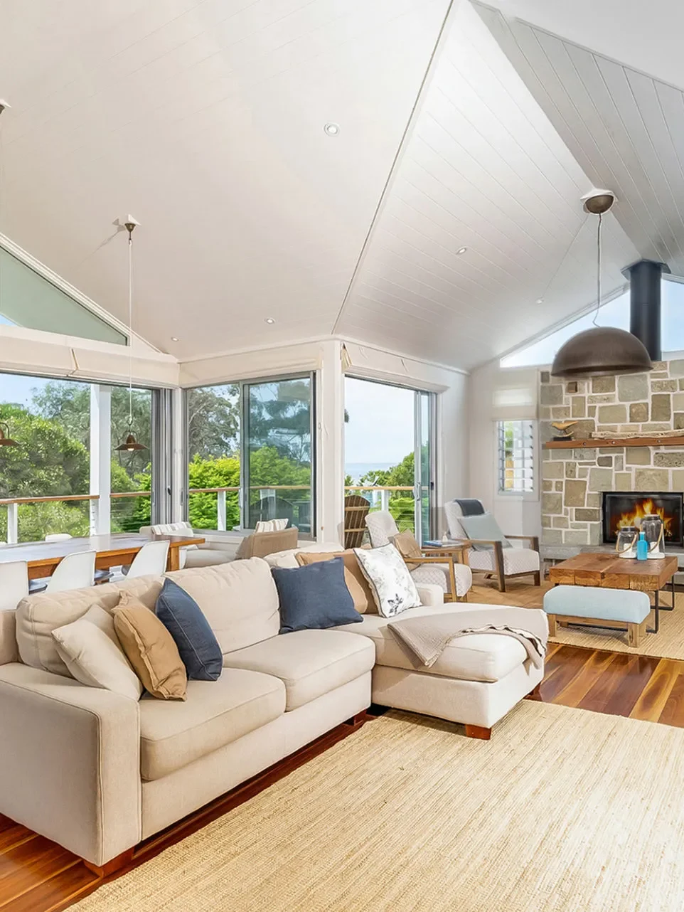 Living room with stone fireplace and vaulted ceiling at Coast at Hyams Beach