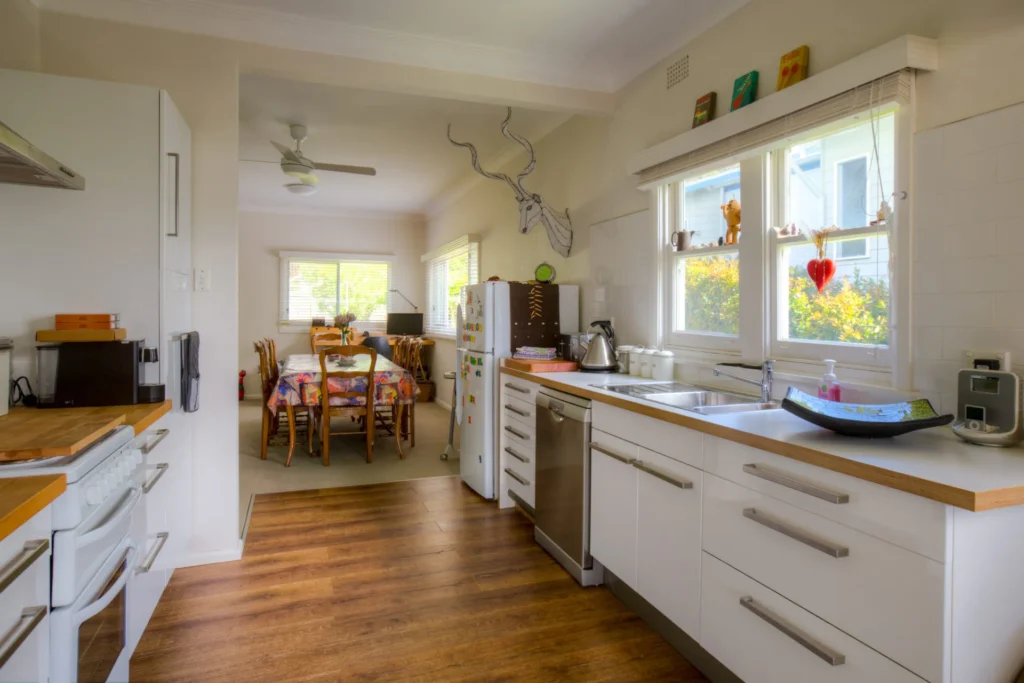 Modern white kitchen with timber floors at Fibro Majestic at Hyams Beach