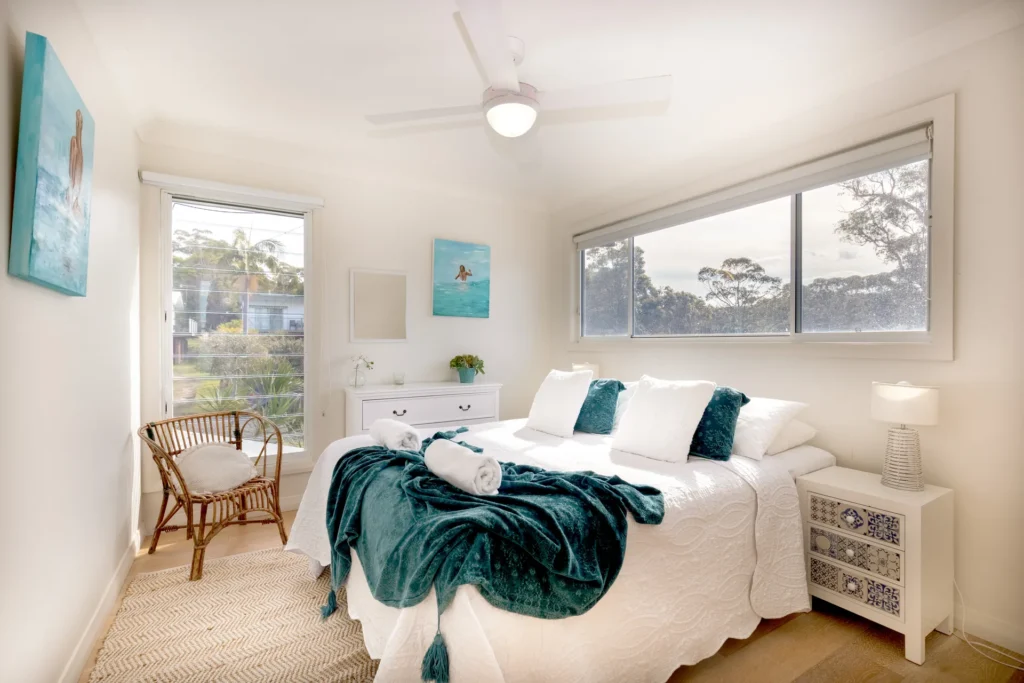 Serene bedroom with teal accents and natural light at Hyamptons Beach House