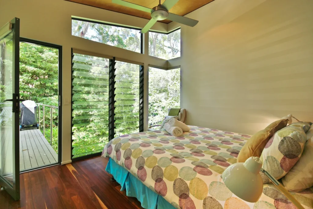 Sun-lit bedroom with forest views and balcony at Hyams Retreat