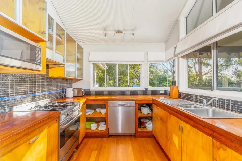 Bright kitchen with wooden cabinetry and mosaic tiles at Iluka