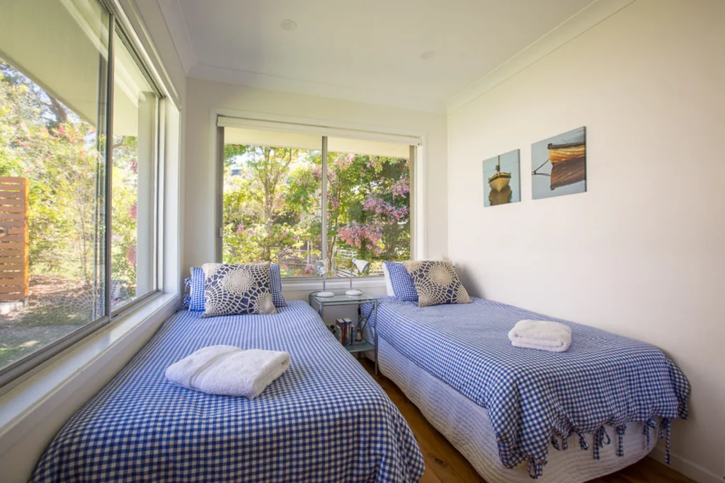 Twin bedroom at Jindalee Beach House with blue bedding and large windows