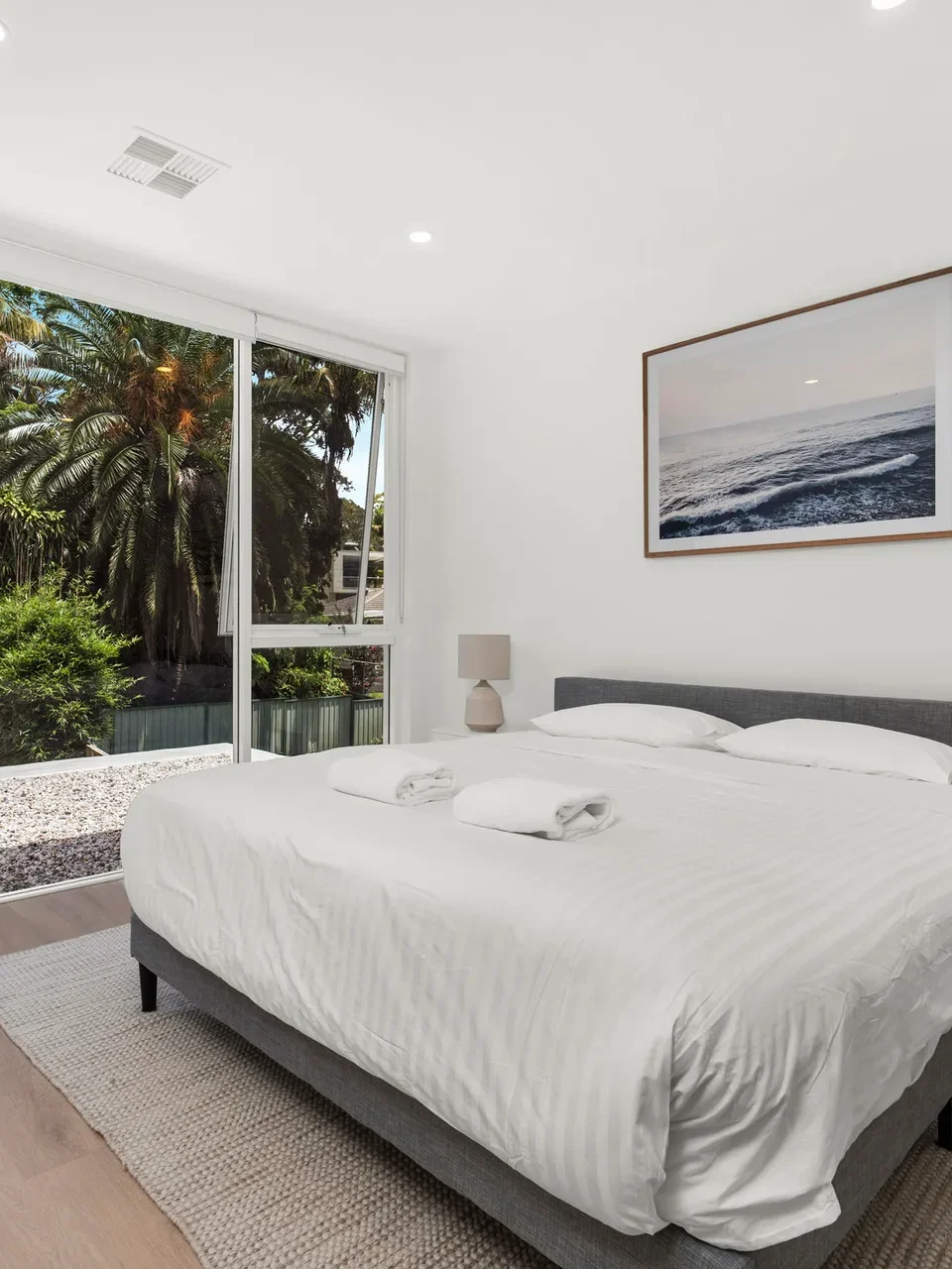a large bedroom with a queensize bed, surrounded by large trees settings