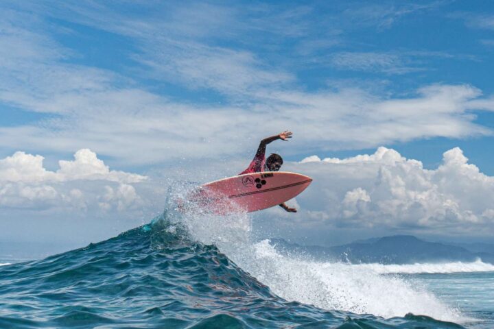 surfer practicing extreme sport above ocean wave in hyams beach