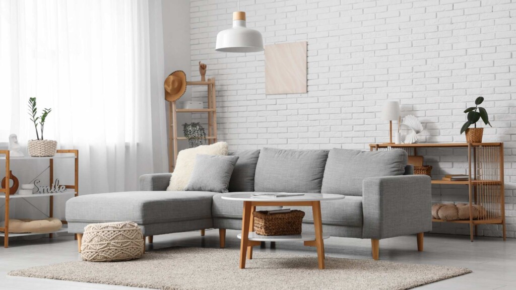 By The Sea Waterfront Accommodation with Private Jetty bright living room with grey sofa, white brick wall and neutral coastal decor