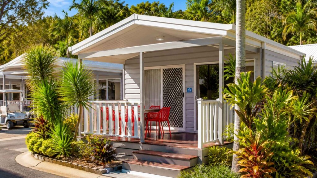 Modern holiday cabin with a covered veranda and tropical landscaping in a holiday park