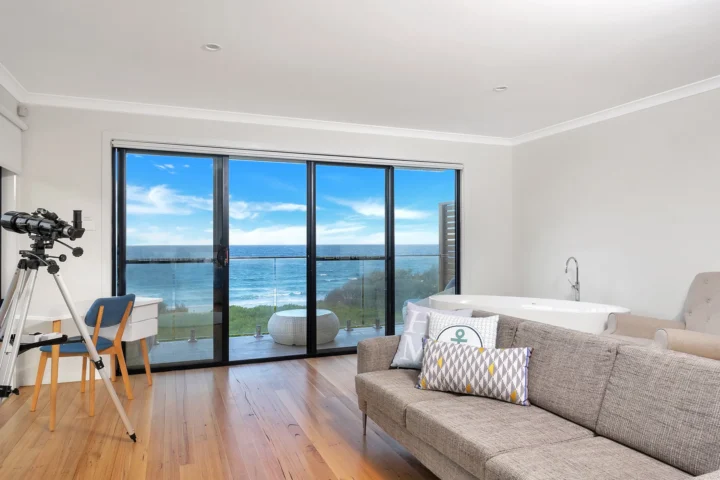 Bright sitting area with a telescope and spa bath at Beach Perfect, Culburra Beach.