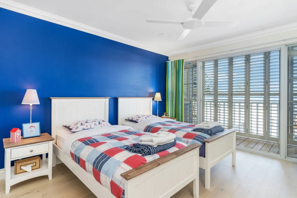 Bright twin bedroom with bold blue walls at The Cape, Culburra Beach