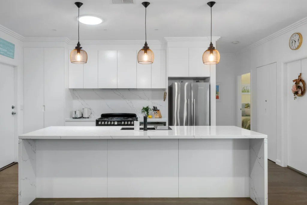 modern kitchen with white island and pendant lights